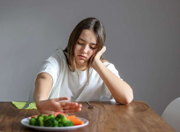 Persona reflexionando frente al espejo "primeros síntomas de trastornos de la alimentación" Psicóloga trabajando con paciente "tratamiento para trastornos de la alimentación" Platos de comida saludable en planificación "prevención de trastornos de la alimentación con nutrición" Familia acompañando a joven "apoyo familiar en trastornos de la alimentación"