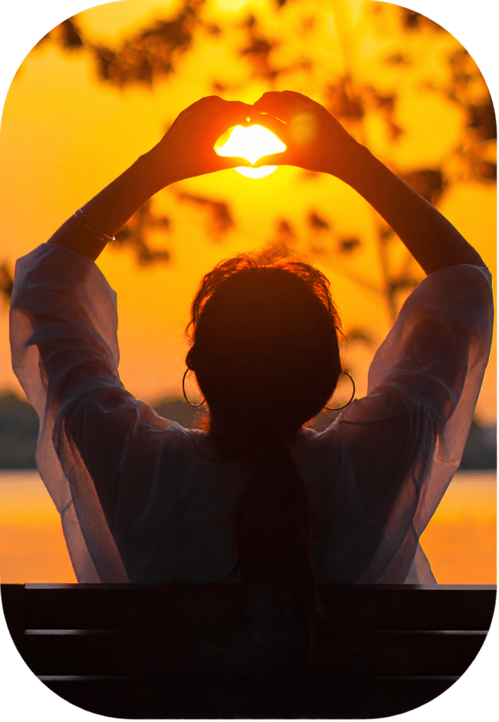 Persona formando un corazón con las manos frente al atardecer, representando un proceso de regulación emocional – Clínica Víctor Navalón.